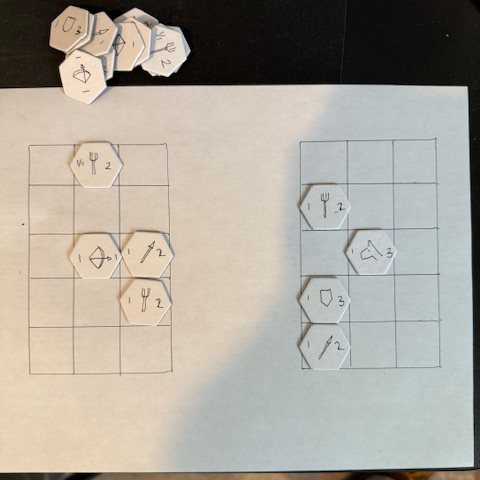 A photo of two grids on a piece of paper with some hex chits