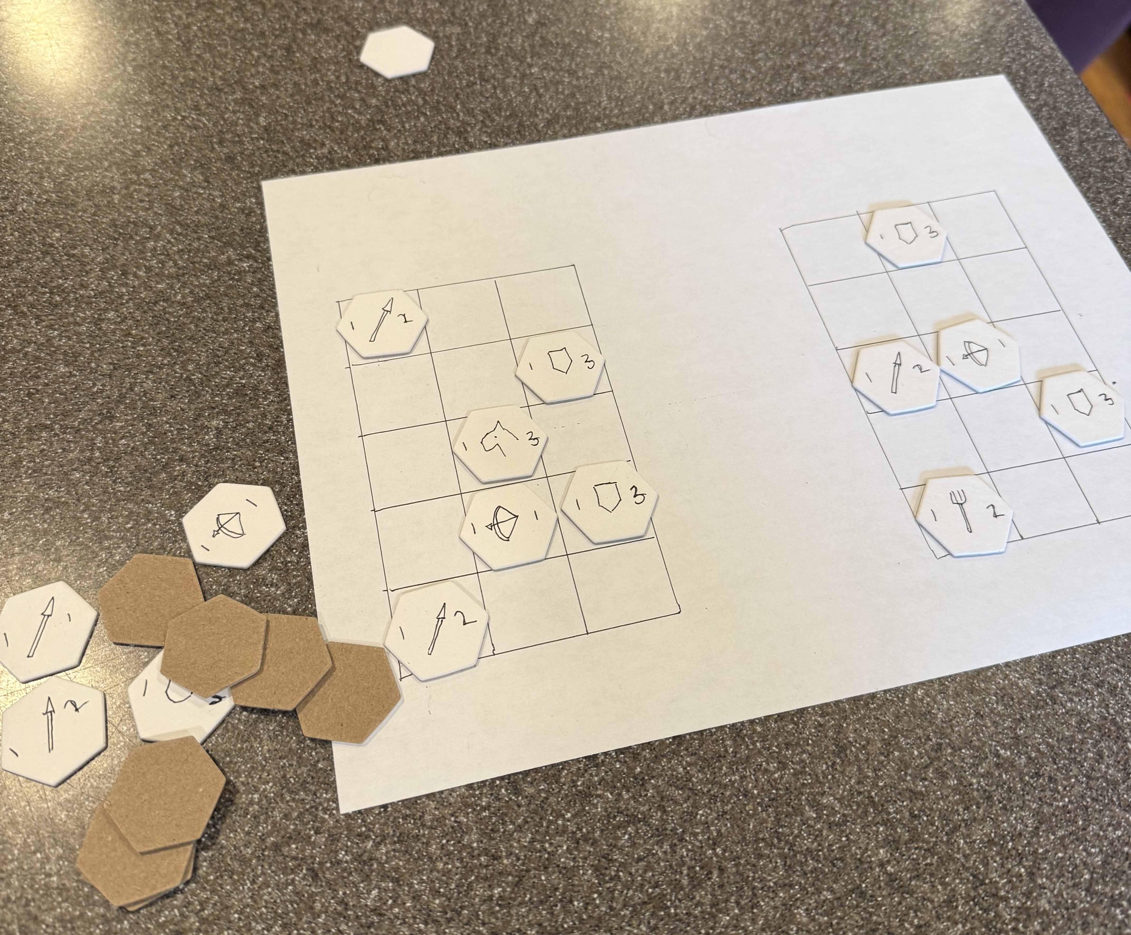 An image of some hand-drawn hex chits on a paper grid